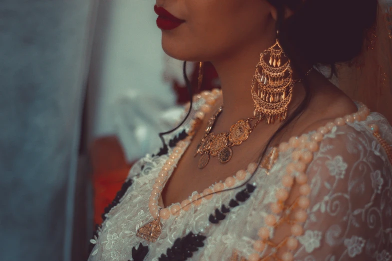 a close up view of an elegant woman wearing gold statement earrings