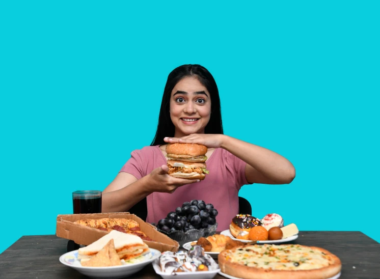 a young lady sitting at a table holding up a hamburger