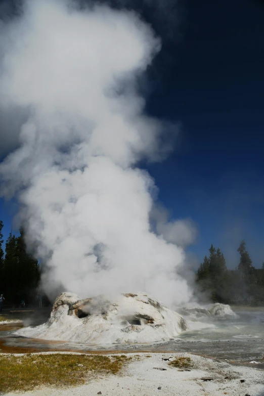 the steam comes out of the geyser at the bottom of a hill