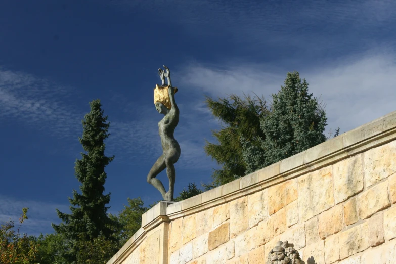 a statue on top of a ledge holding an object in its hands
