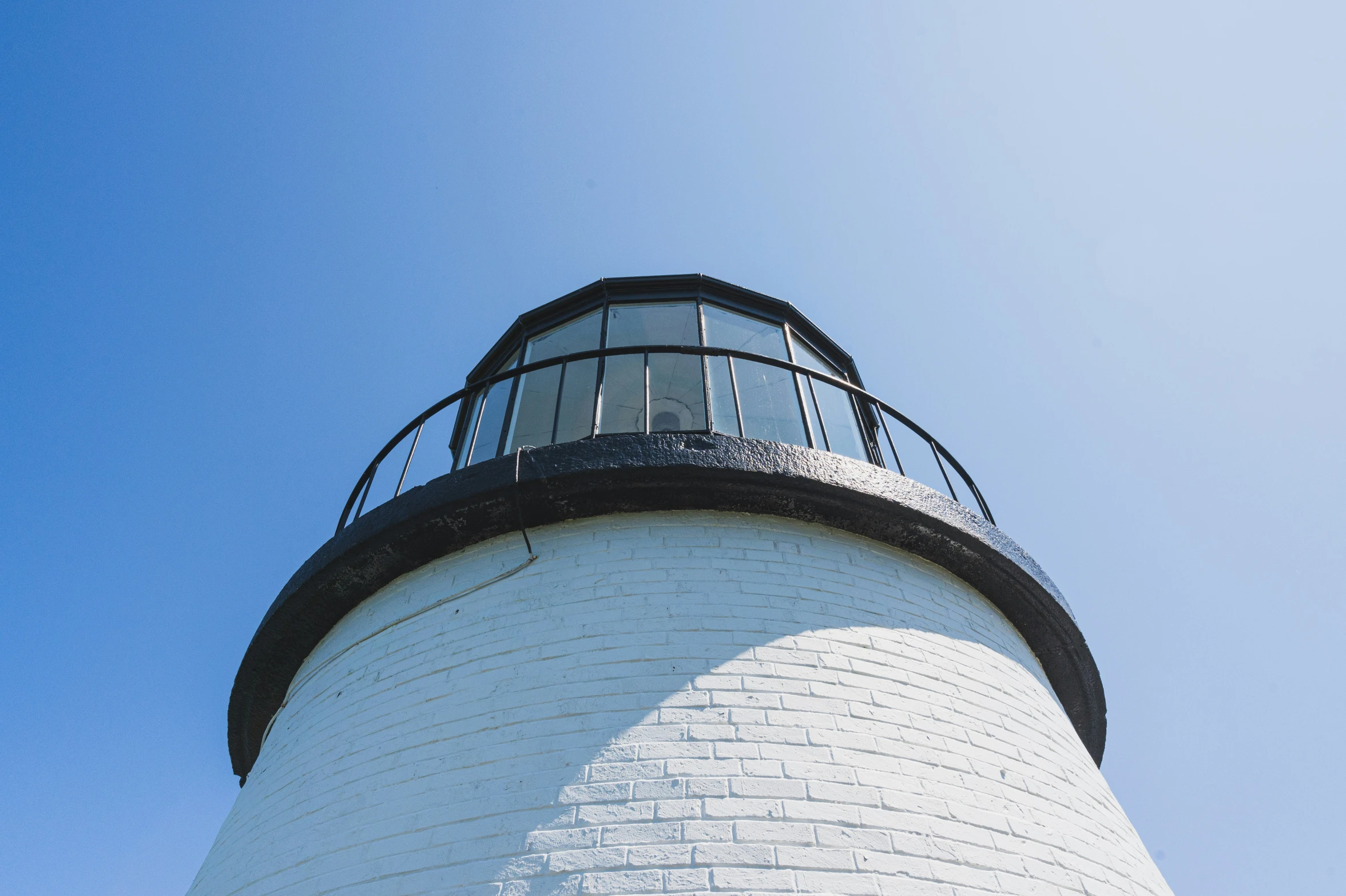 a white and black lighthouse with a blue sky in the background