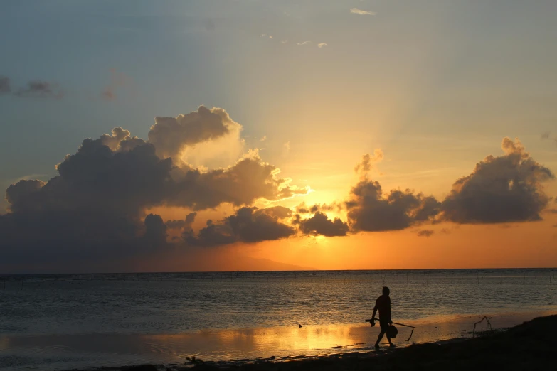 people walking along the ocean in front of a sunset