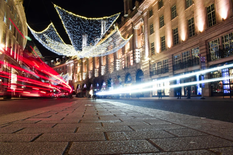 a nighttime scene with lights, a double decker bus and a clock tower