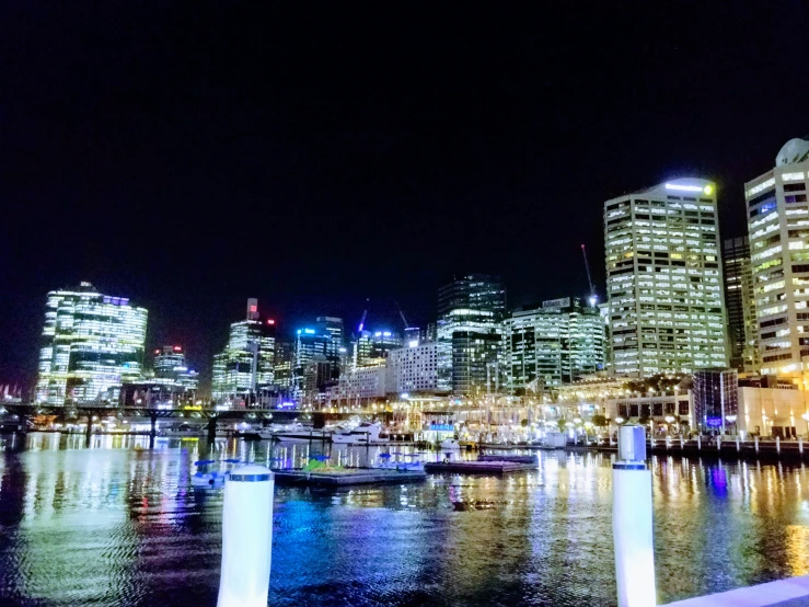 lights on skyscrs at night are reflecting off the water