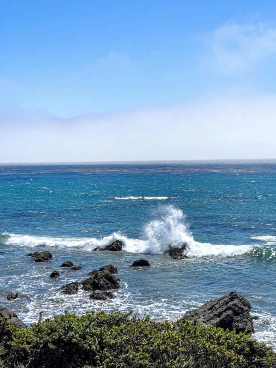 a wave crashes at a rocky beach area