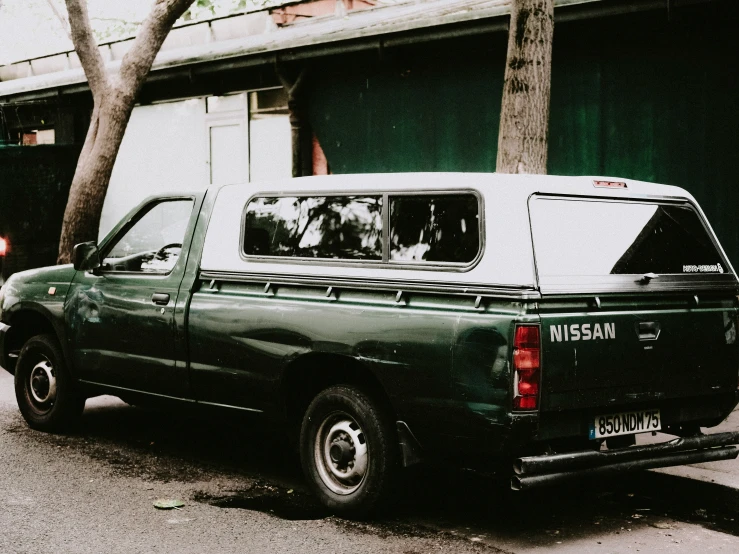 a large green truck on the street next to trees
