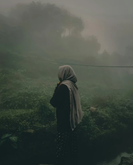 a woman with a head covering walking on a foggy day