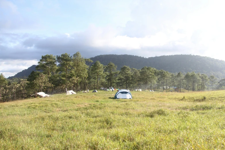 tents set up in an open field under a mountainous sky