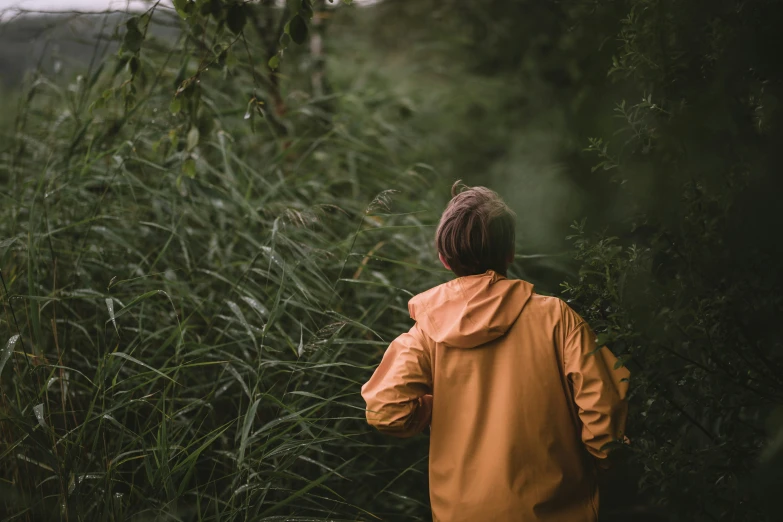 a woman walking in the rain through tall green grass