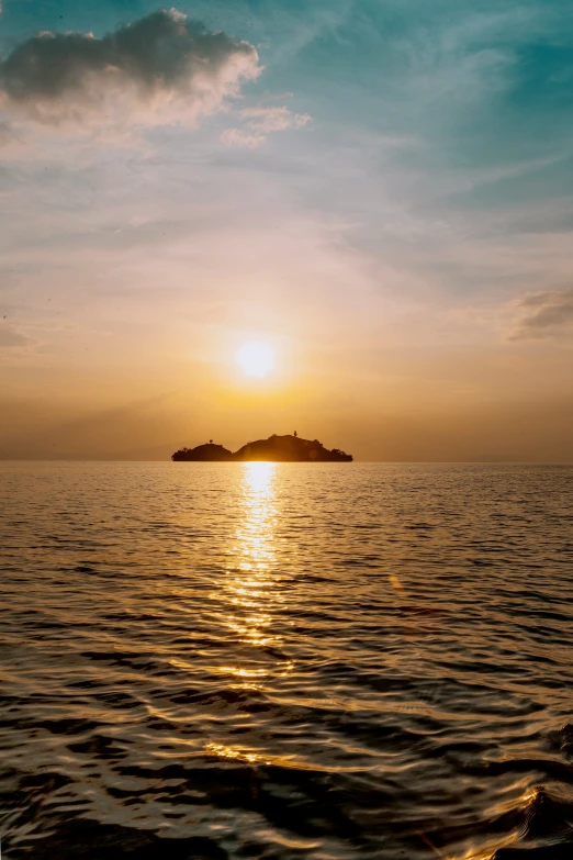 an island sitting out in the middle of the ocean at sunset