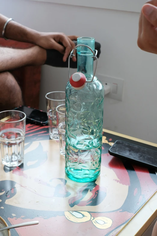 a very large glass bottle with a few glasses in it