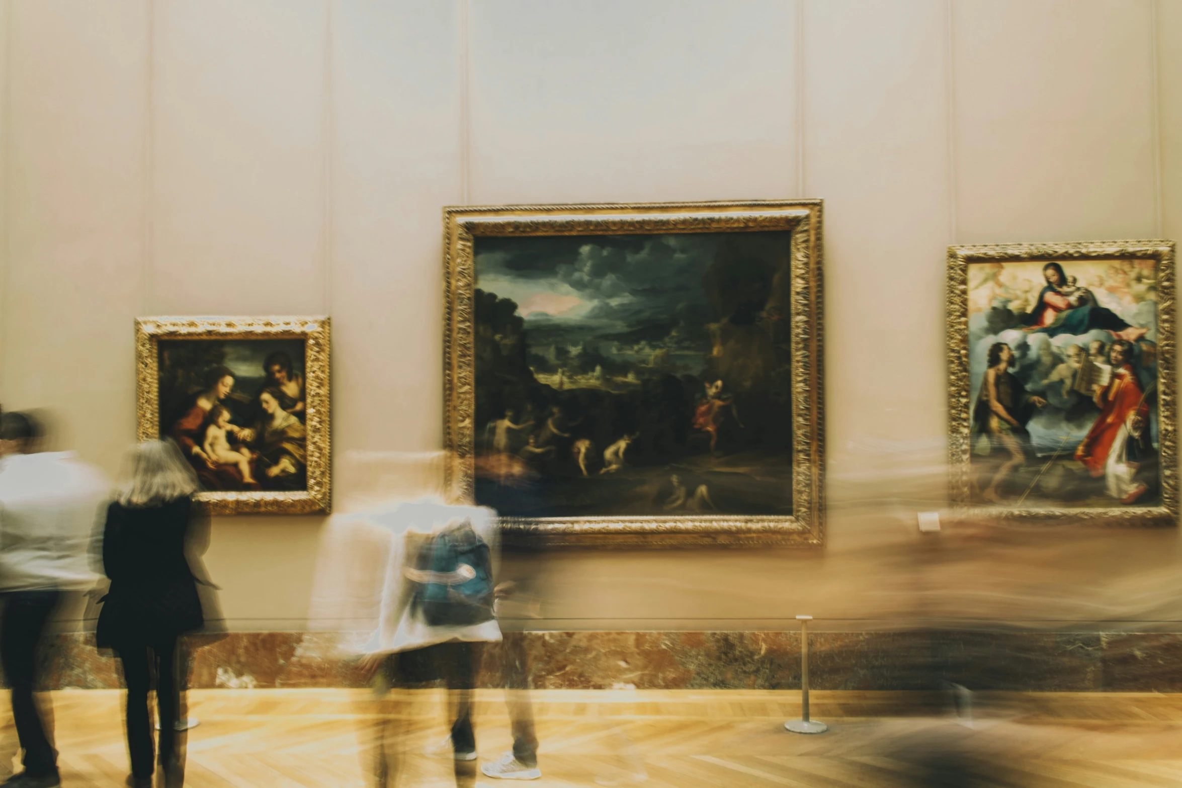 a group of people standing around paintings in an art museum