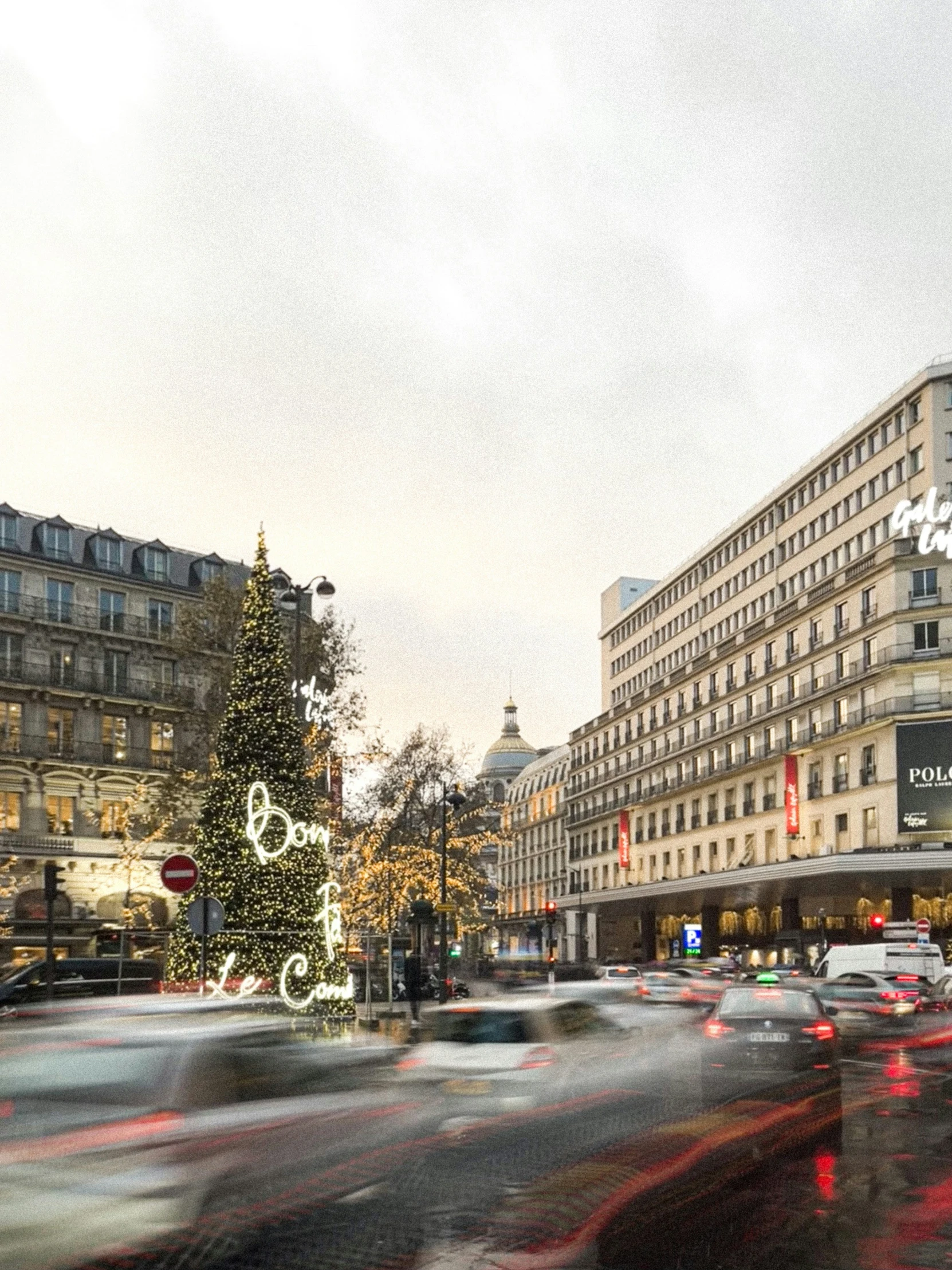 a large christmas tree stands in the middle of a busy city street