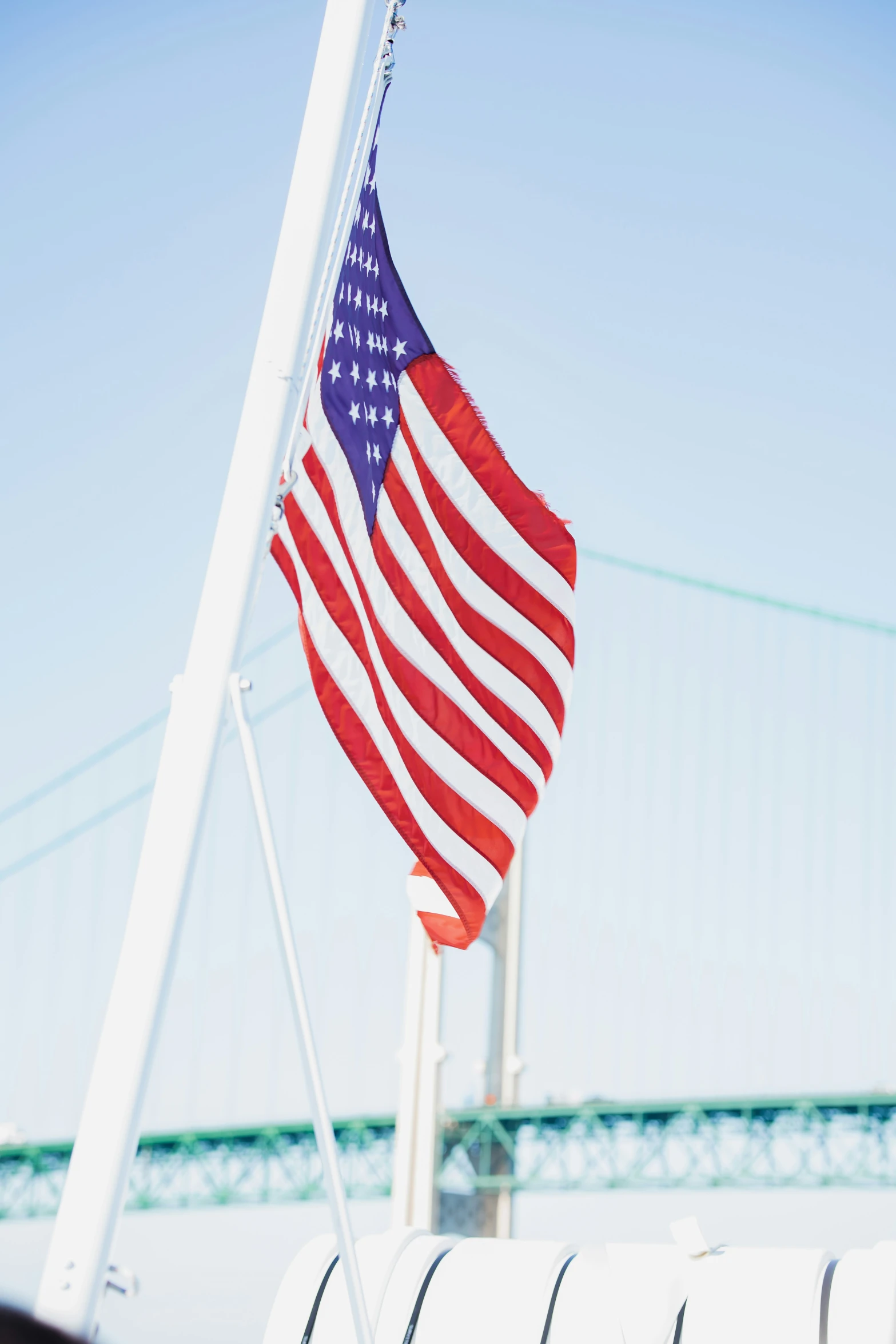 a flag flying on the back of a boat near a bridge