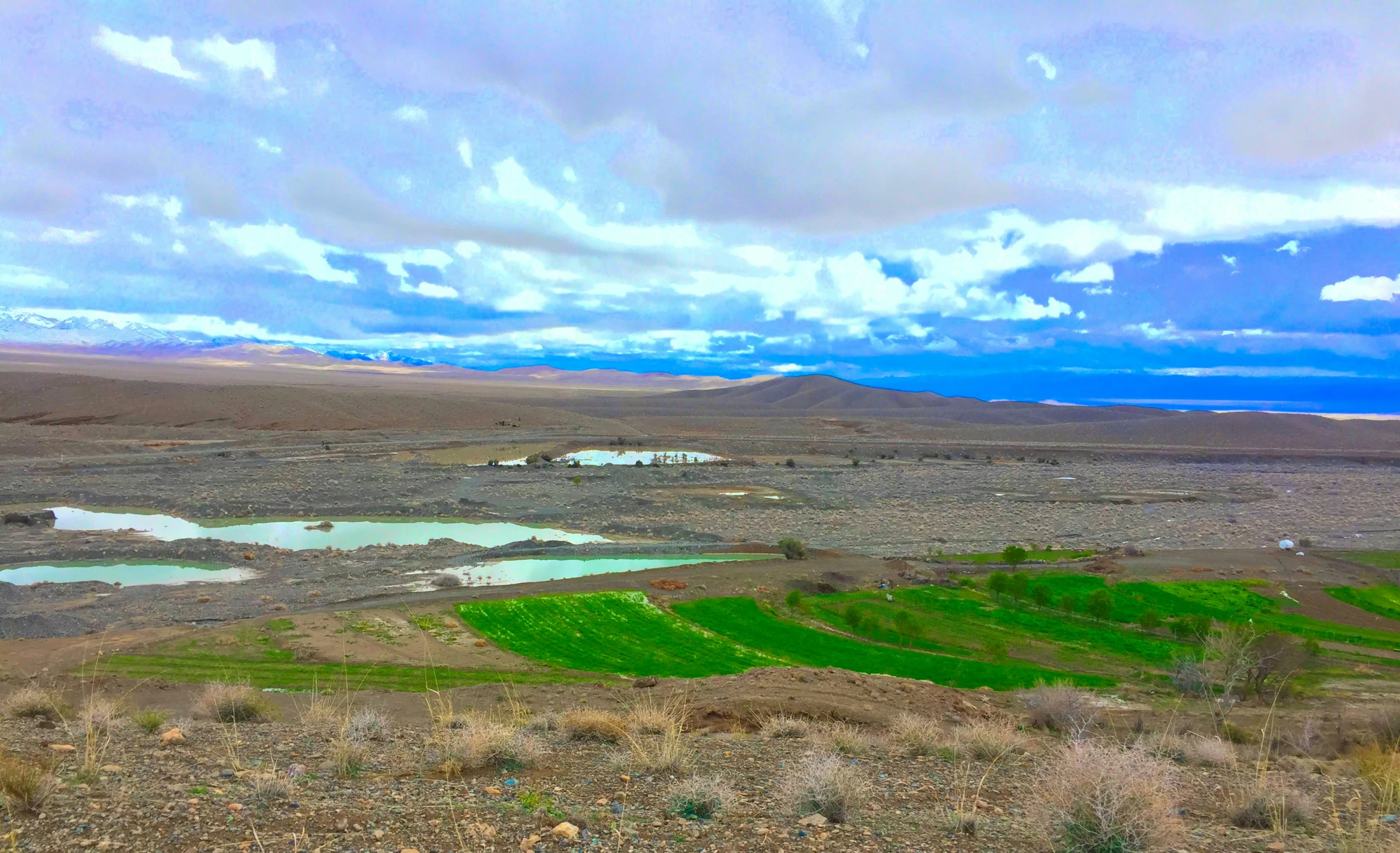 a barren landscape with hills and lakes on the left