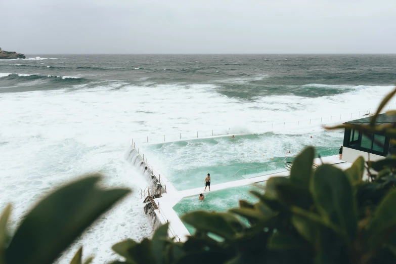 an empty swimming pool sitting next to the ocean