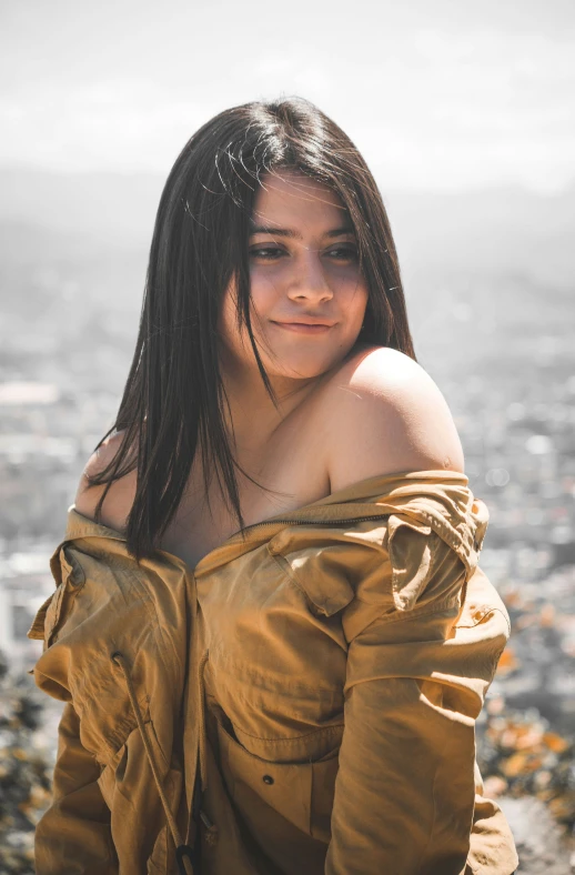 a girl with long hair wearing a brown shirt looking over a city