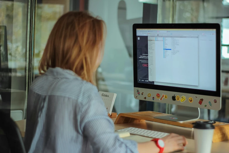 woman sitting in front of a desktop computer monitor with a small keyboard