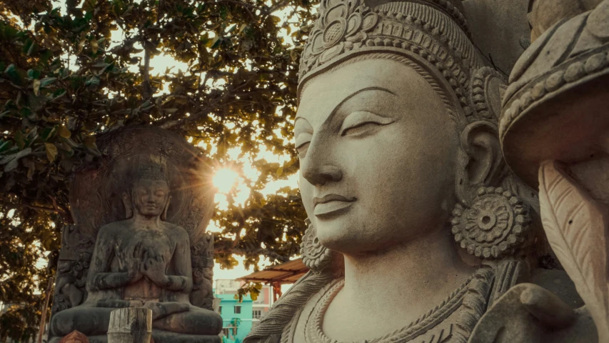 a large white statue surrounded by statues under a tree