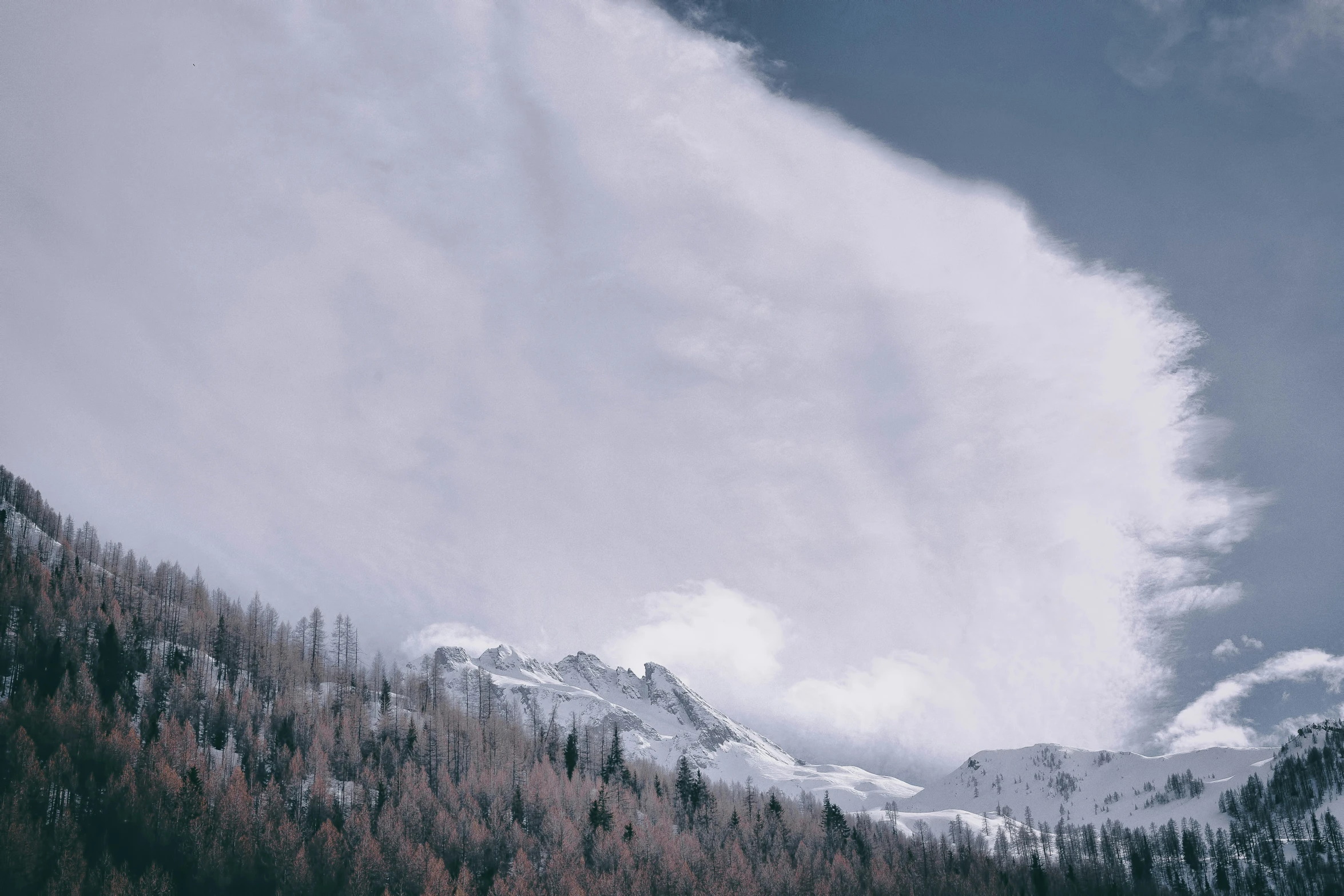 the sky is a very cloudy, snow covered mountain