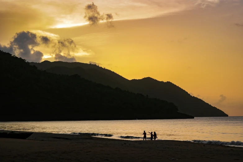 two people walking towards the ocean at sunset