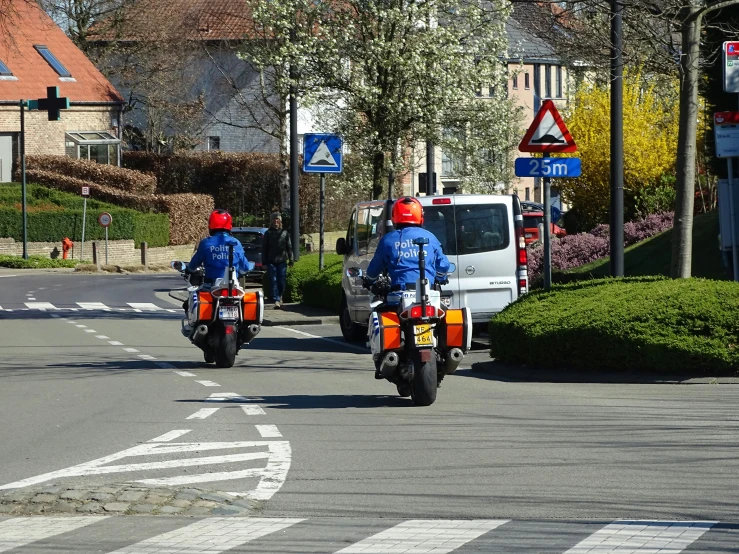 two people on motorcycles traveling down a city street