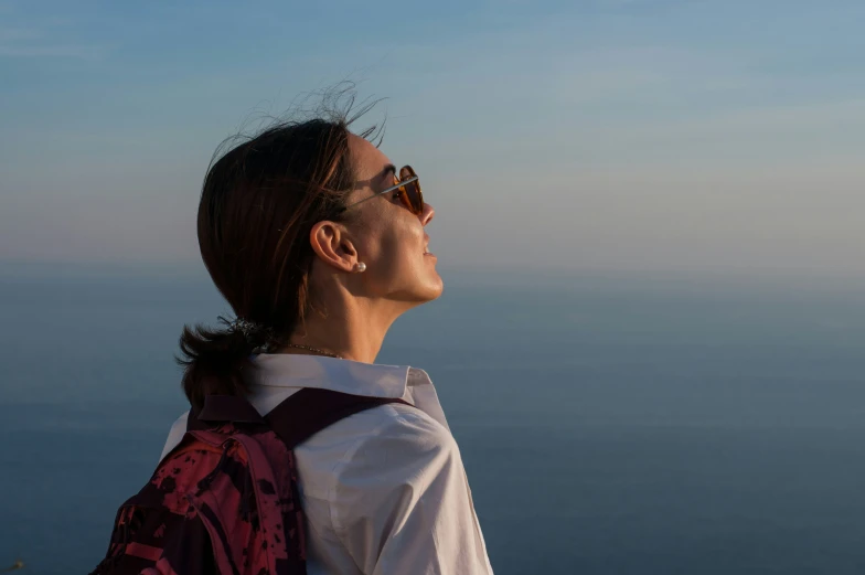 a woman stands on top of a mountain above the water