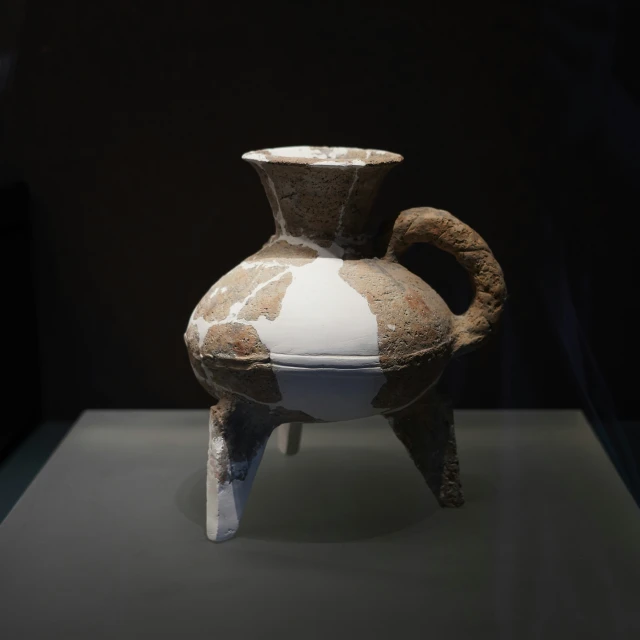 an old brown and white vase is sitting on display