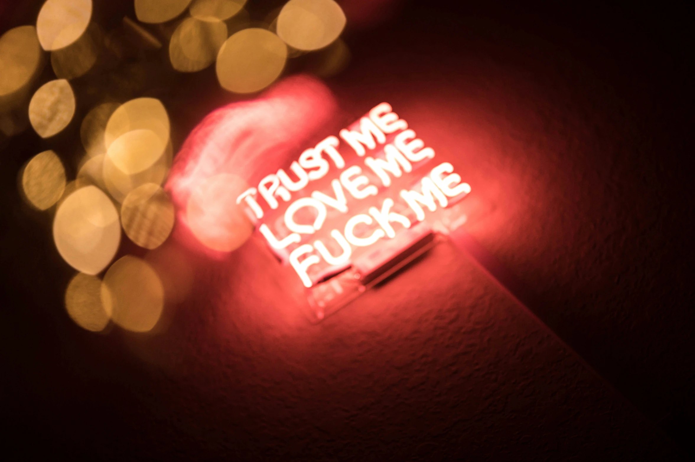 the back of a neon sign reads trust me, love me, and ing me