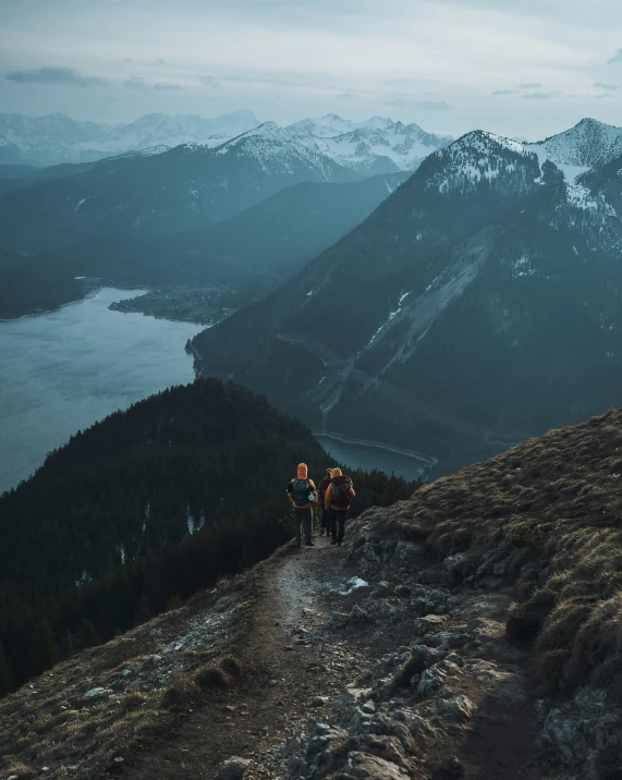 two people hike up a snowy mountain in the background