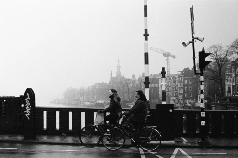 a man and a woman riding bikes down a rain soaked street