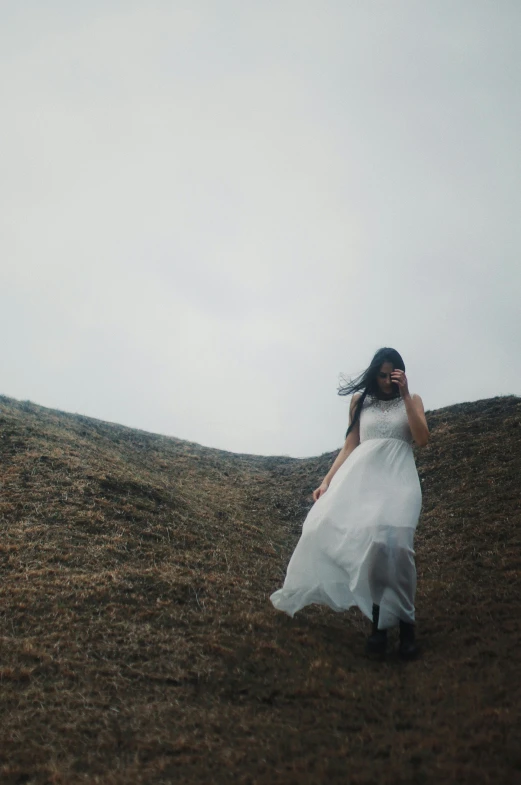 a woman is walking in a white dress and she is holding the other hand up