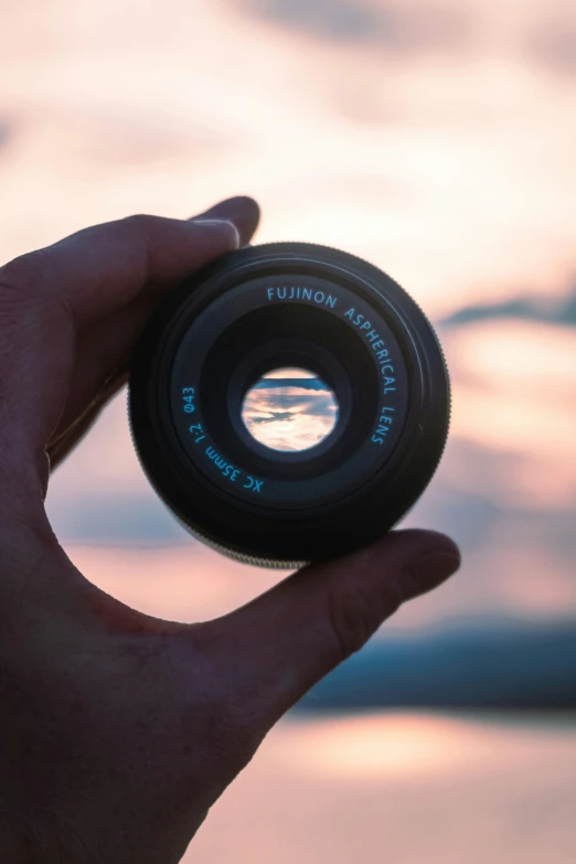 a person holds their camera lens in their hand