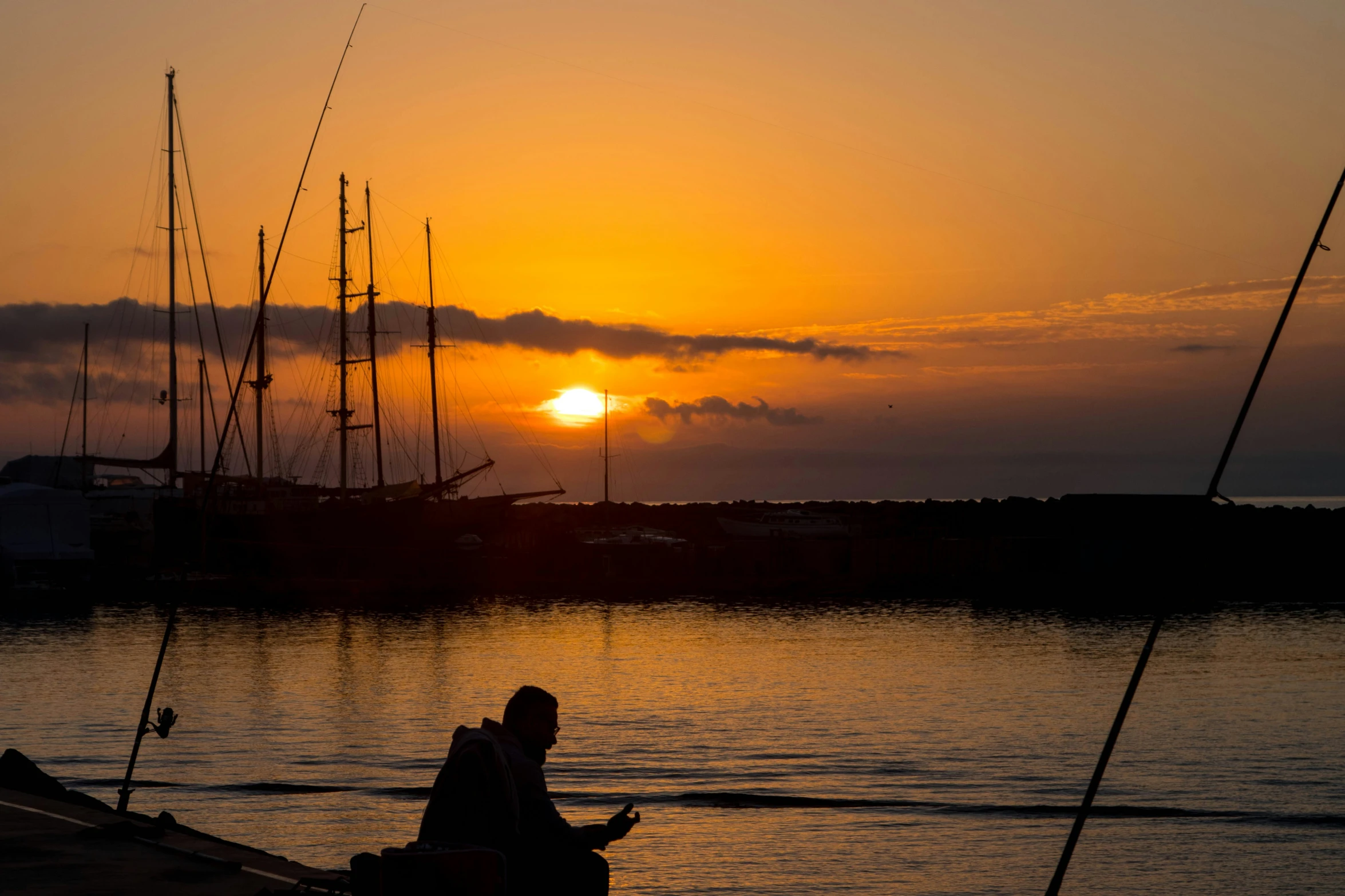 a man sitting on a dock watching the sun go down