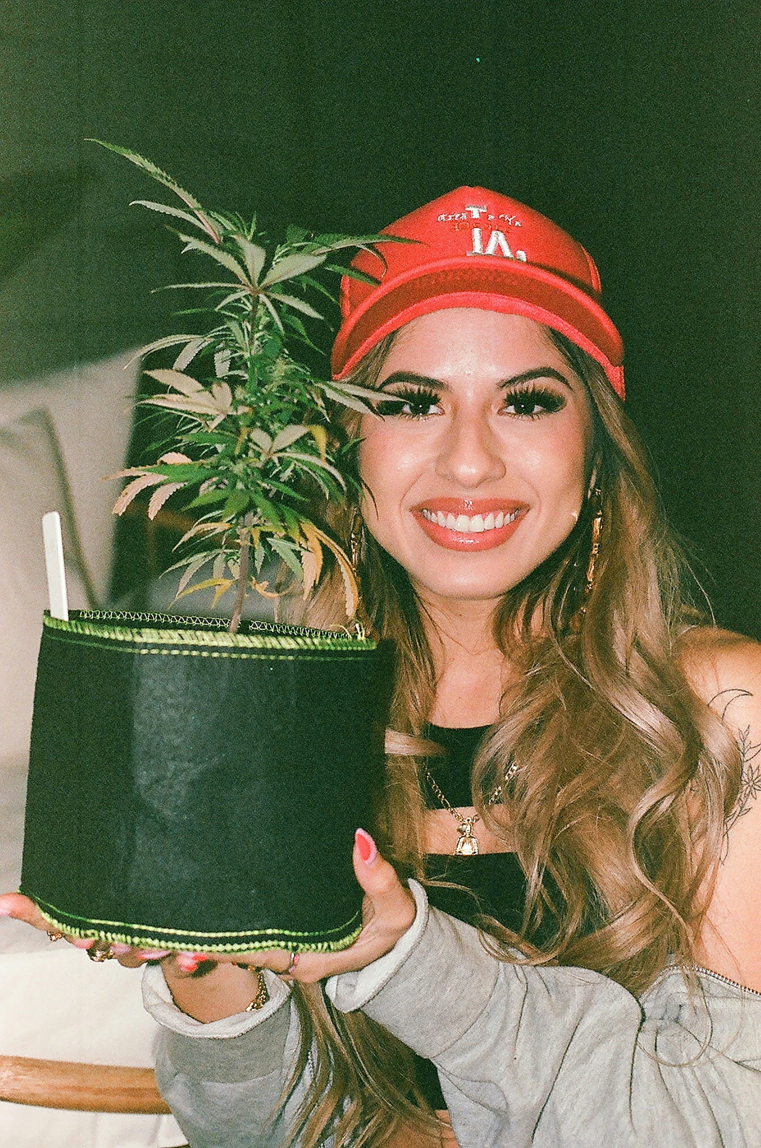 girl holding plant with headband smiling and wearing red scarf