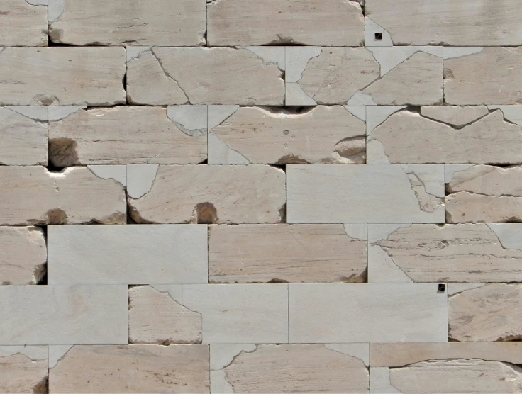 a wall of gray and white stones with holes