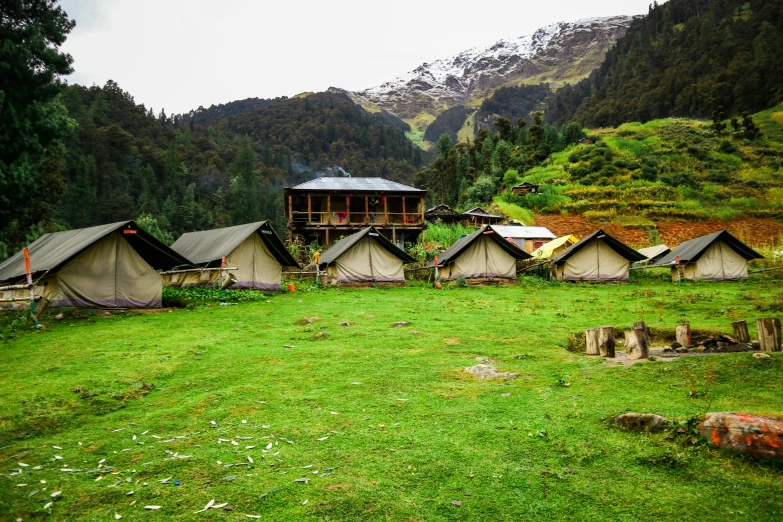 tents with pitched roofs stand in a valley