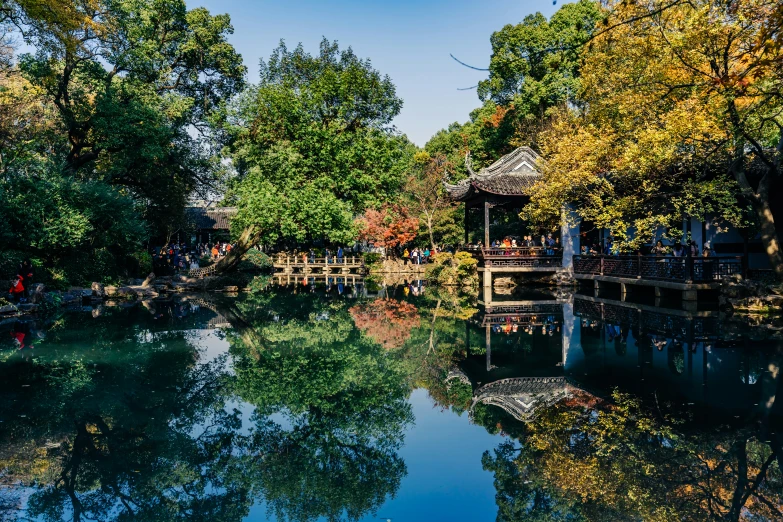 an open area with people sitting on a bench over a river