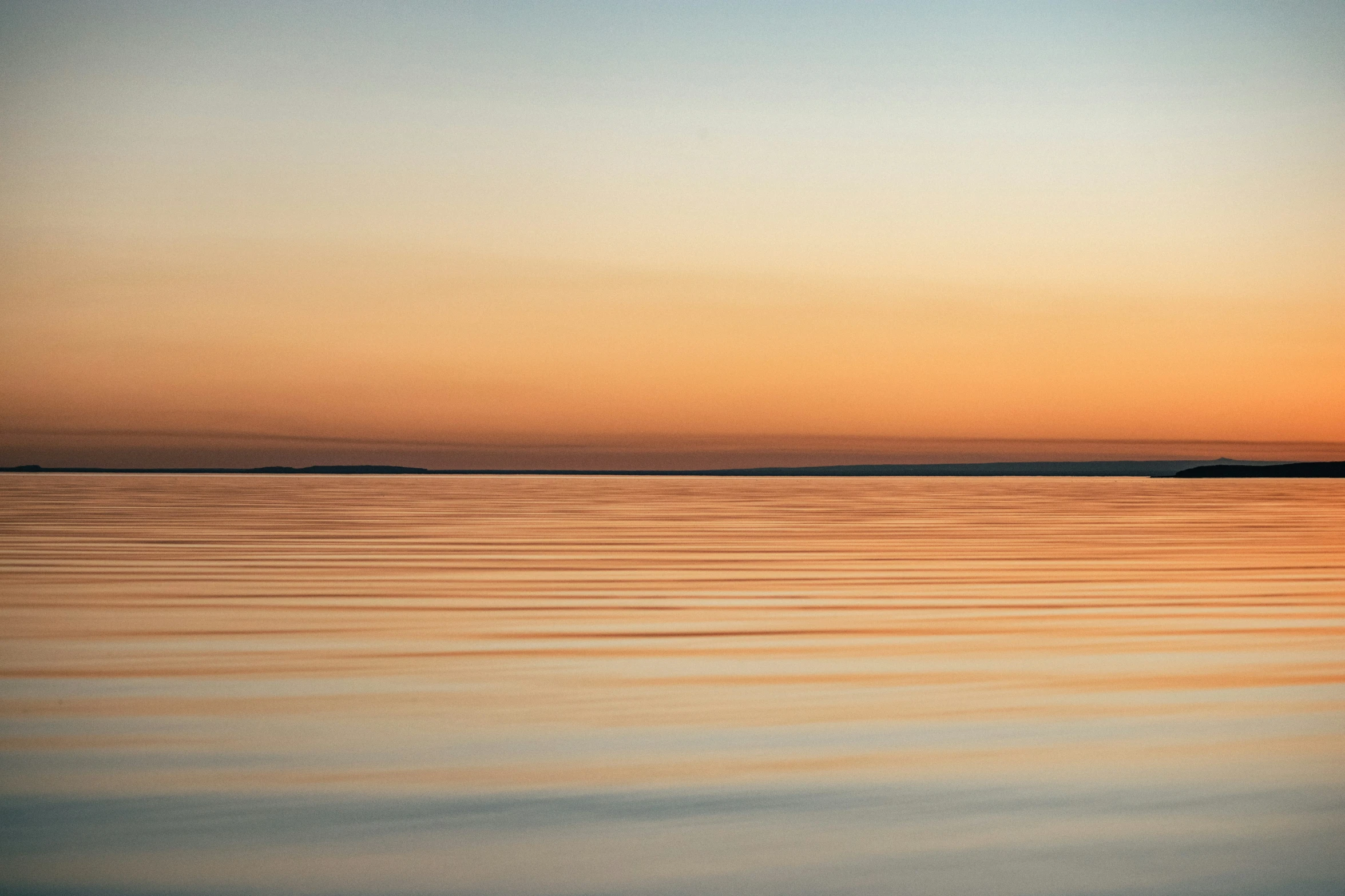 the ocean and sky at sunrise with reflections on water