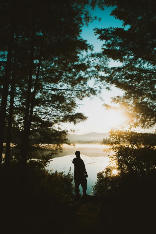 a man standing on a body of water under trees