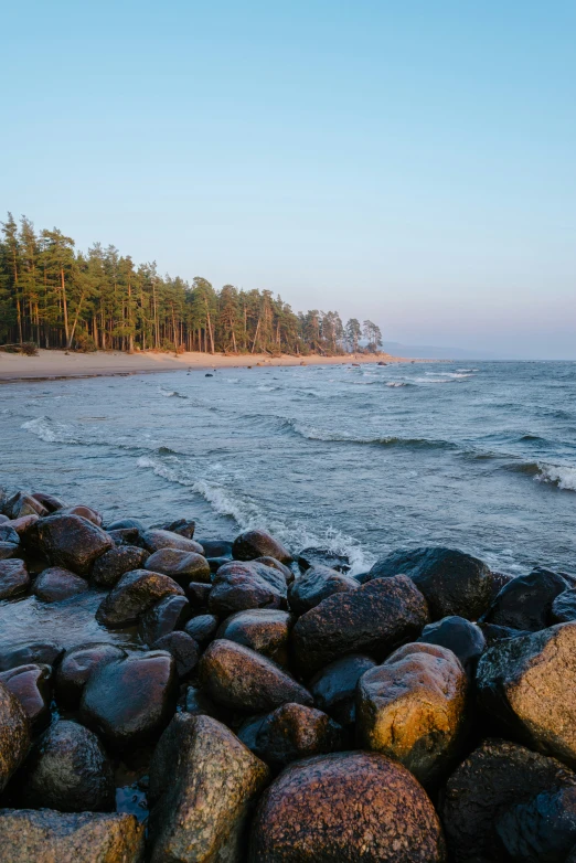 a beach covered in lots of large rocks next to the ocean