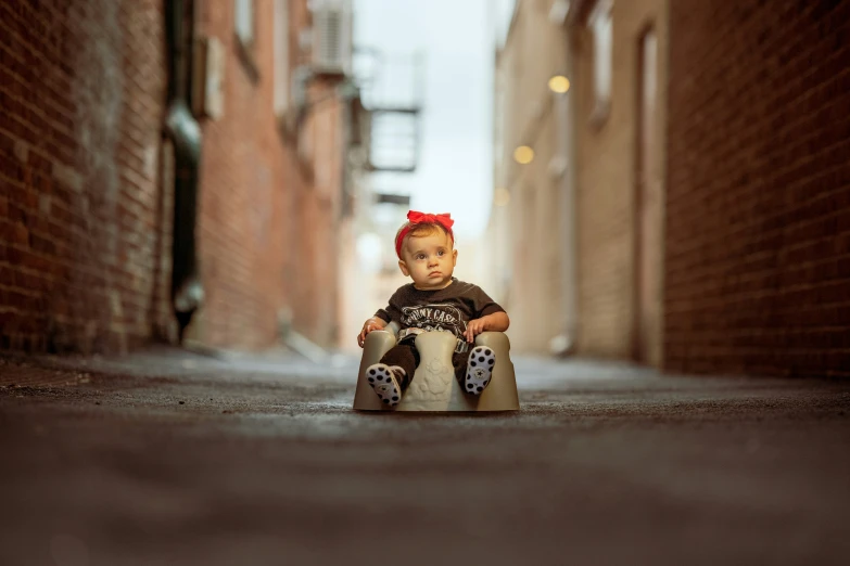 a young child sitting on the sidewalk in the alleyway
