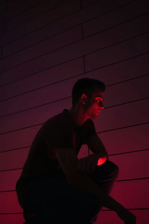 a man sitting on the floor in front of a red brick wall