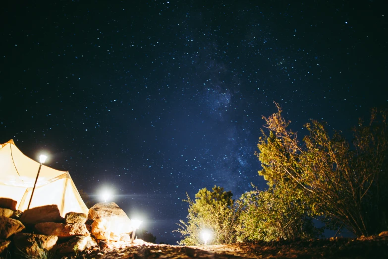 two tents are lit up in the night with some stars above them