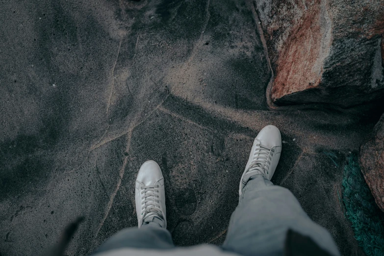 person standing on the pavement in white shoes