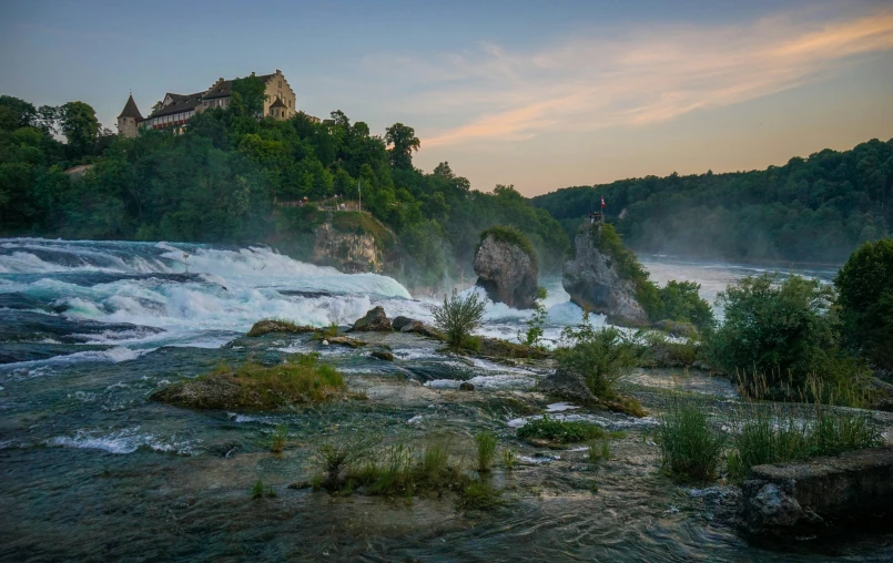 a castle is perched high in the mountains near a river