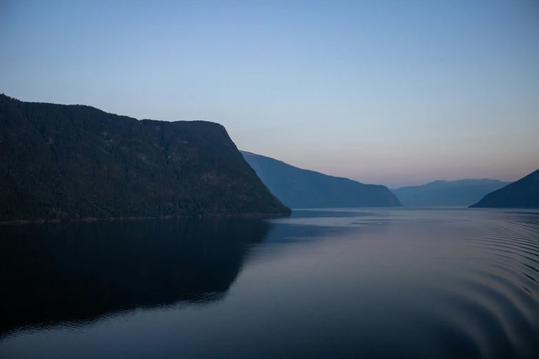 mountains surrounding a body of water with a blue sky