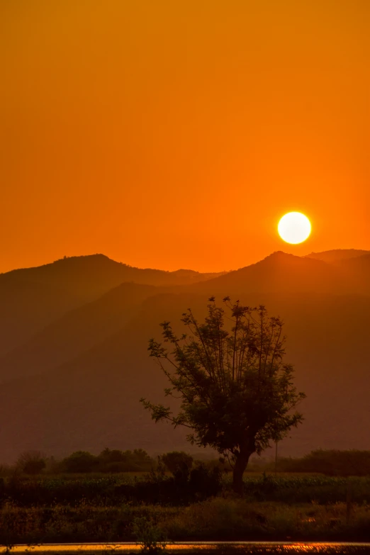 the sun shining over the horizon in front of mountains