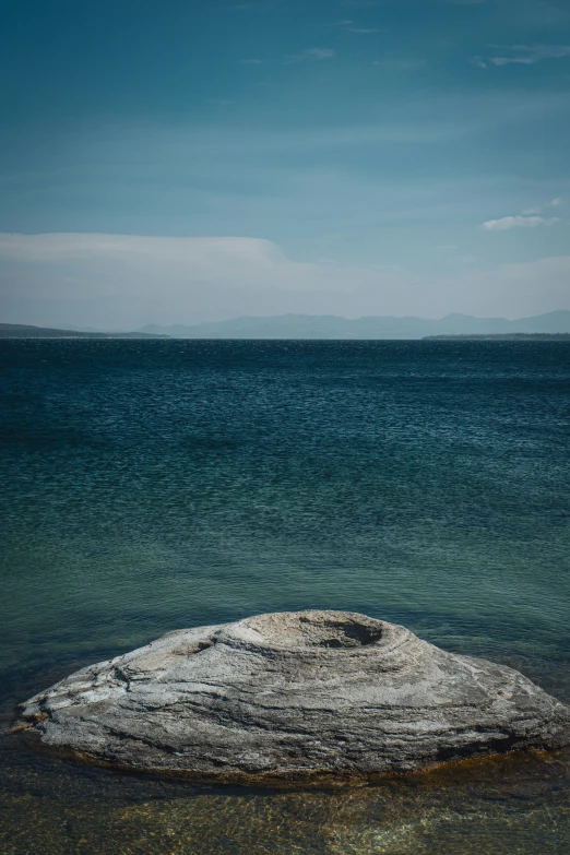 a large rock sitting on top of a body of water