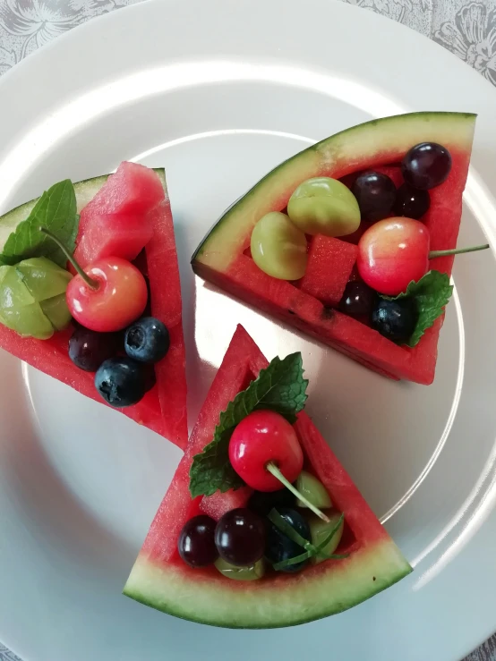 slices of watermelon and cherry pizza on white plates